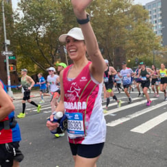 SoleMate running the TCS NYC Marathon with a big smile and waving!